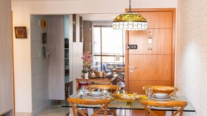 A dining area with a glass table, wooden chairs, and a hanging light fixture. - Paraiso do Atlantico #102d - Style by Carpediem (Cabedelo)