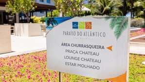 A sign for the Paraíso do Atlântico Club Residence indicating the Churrasqueira area, including the Praia Chateau and Lounge Chateau. - Paraiso do Atlantico #102d - Style by Carpediem (Cabedelo)