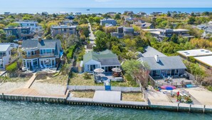 Un quartier résidentiel situé sur la côte, avec des maisons, un quai et une vue sur l’océan.
