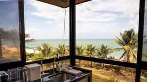 A kitchen with a view of a beach, a sink, and a countertop with kitchen items. - Alta Marine Housi Joao Pessoa by Carpediem (João Pessoa)