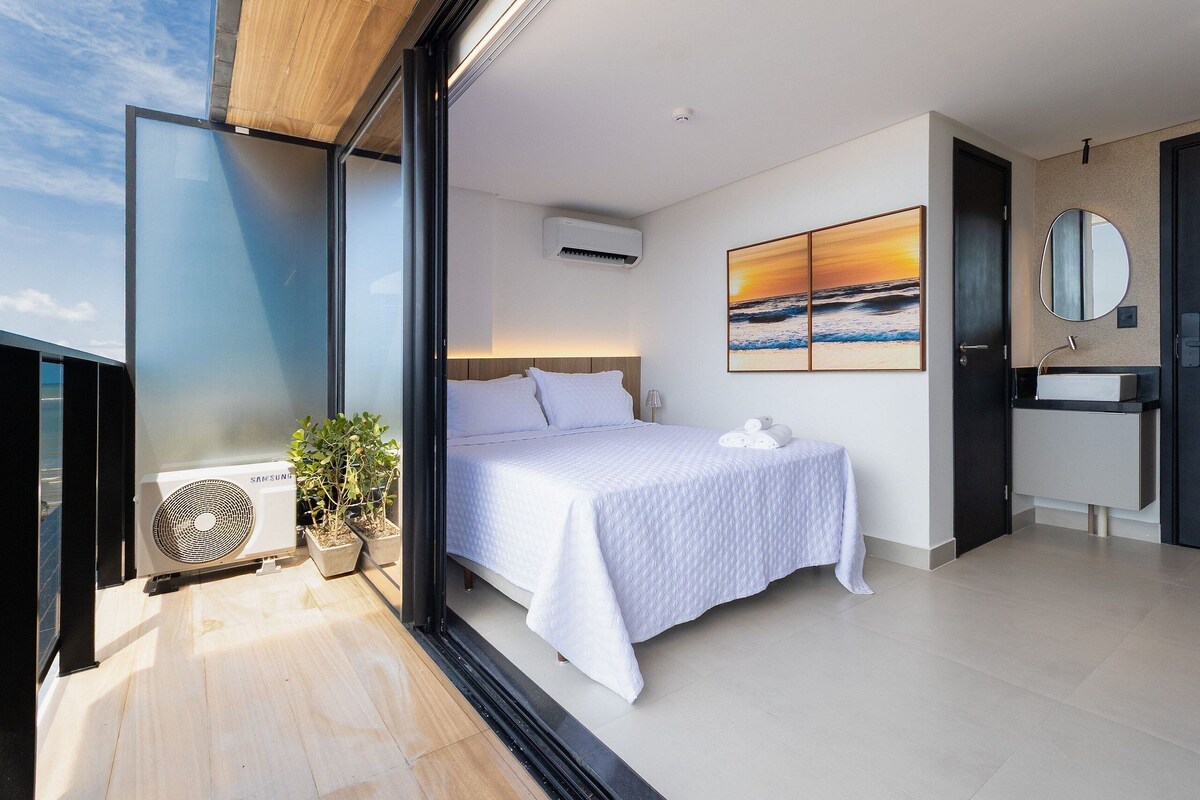 A modern bedroom with a bed, air conditioning unit, and a painting of a sunset.