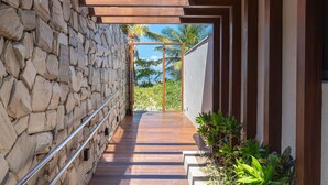 A corridor with a stone wall, wooden floor, and a metal railing. - Alta Marine Housi Joao Pessoa by Carpediem (João Pessoa)