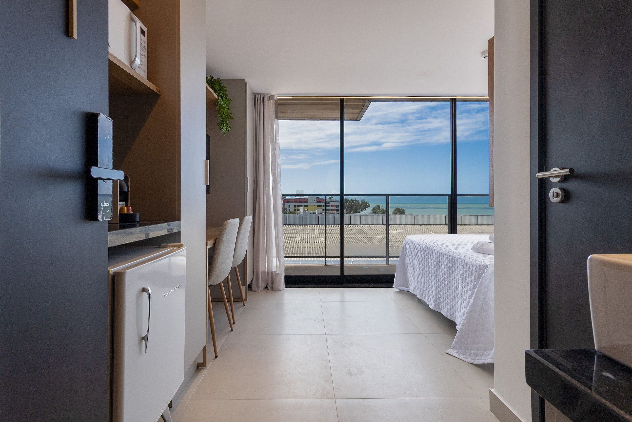 Une chambre d’hôtel moderne dotée d’un balcon, d’un coin repas et d’une cuisine.