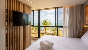 A hotel room with a large window offering a view of the beach and palm trees. - Alta Marine Housi Joao Pessoa by Carpediem (João Pessoa)