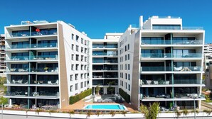 Un hotel moderno a più piani con balconi, una piscina e aree salotto all'aperto.