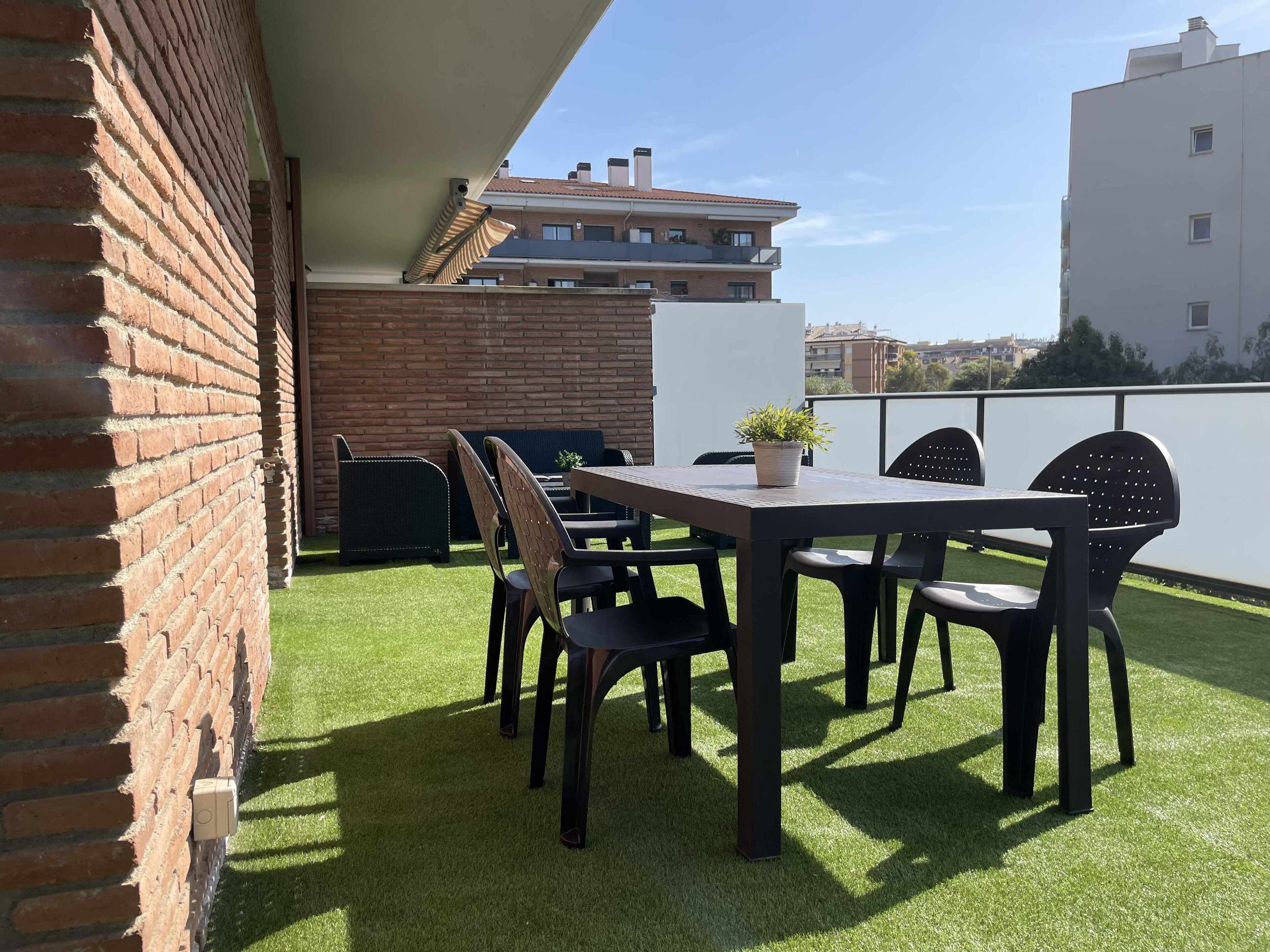Eine Dachterrasse mit Backsteinmauer, einem Tisch mit Stühlen und einem Blumentopf.