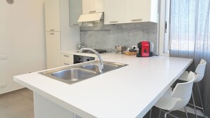 Een moderne keuken met een wit aanrecht, een roestvrijstalen spoelbak en witte keukenkastjes.