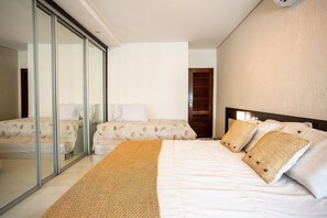 A modern bedroom with a large bed, a smaller bed, and a glass partition.