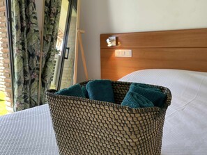 A wicker basket with teal towels on a bed with white sheets. - Renovated apartment near the beach (Lloret De Mar)