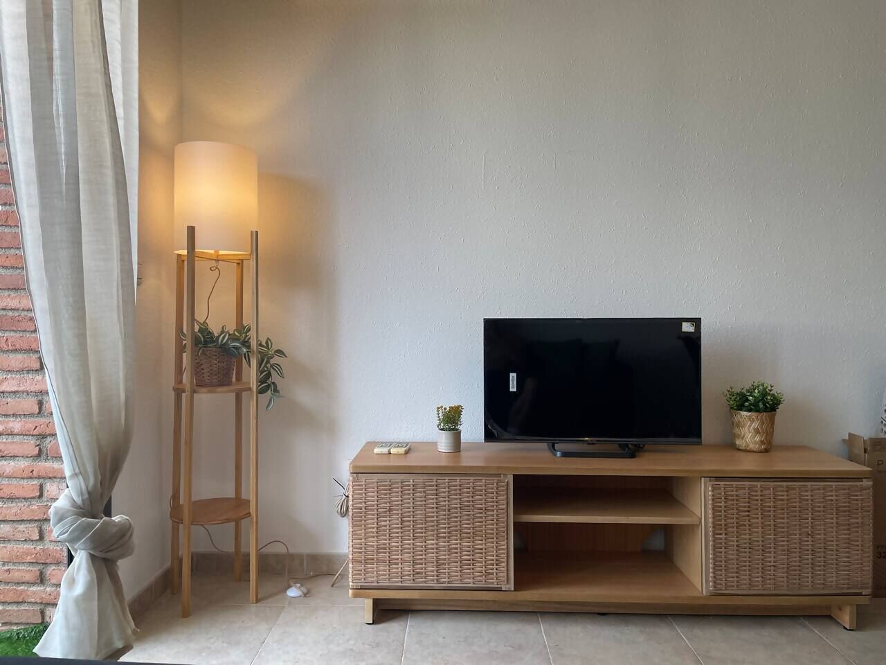 Un mueble de madera con un televisor de pantalla plana, dos cestos de mimbre y una planta pequeña.