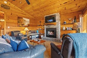 A cozy log cabin interior with a fireplace, leather furniture, and a rustic decor. - 10 Min from Dollywood! 2 Fireplaces •Private Hot tub• Amazing Mtn Views! (Sevierville)