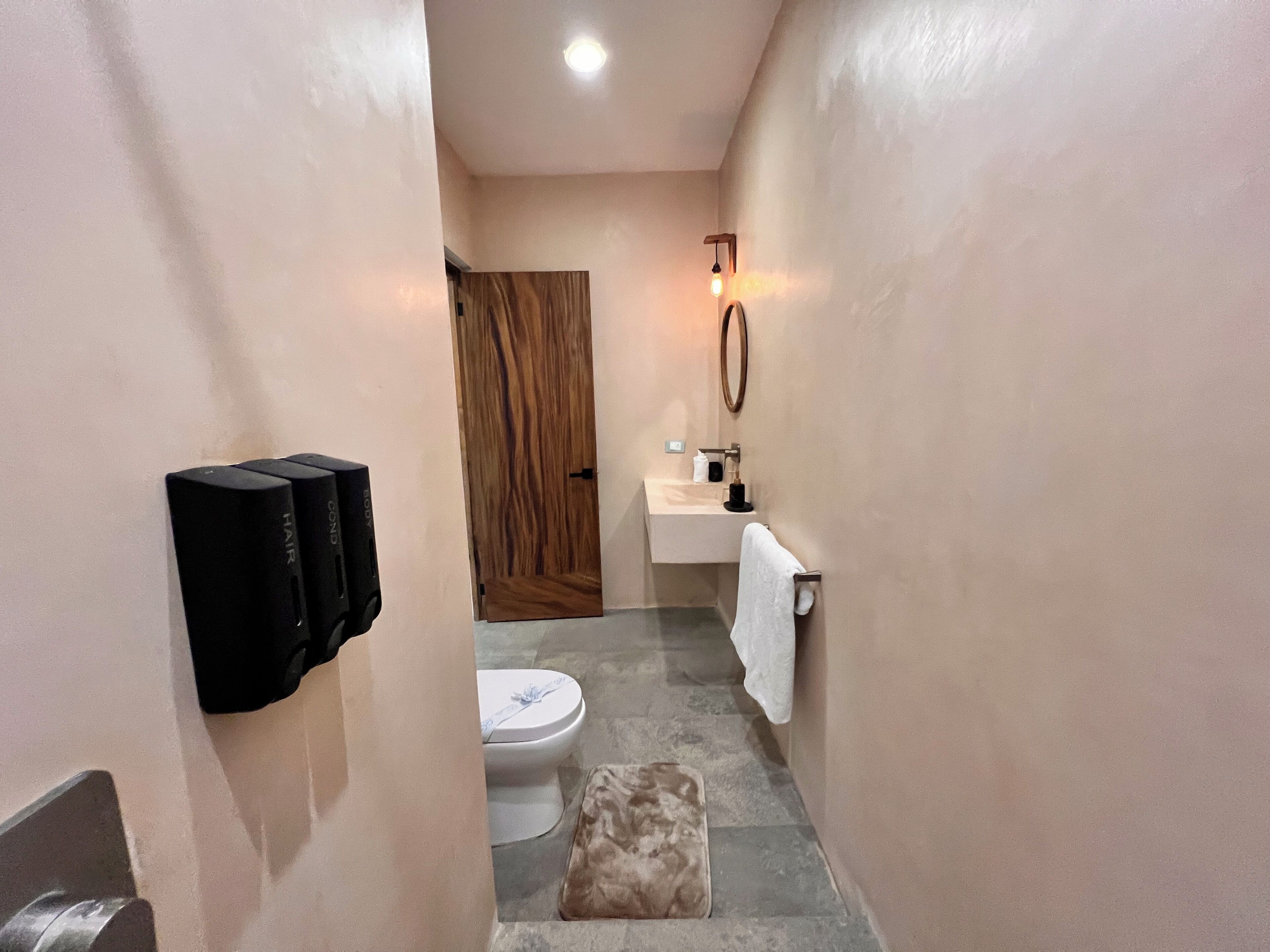 A narrow bathroom with a toilet, sink, and towel rack.