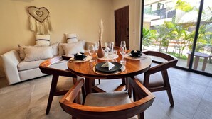A dining area with a round wooden table, six chairs, and a sofa with cushions. - Private and Peaceful Apartment 1BD 1BR (Tulum)