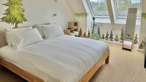 Un dormitorio con una cama grande, un ventilador de techo, un tragaluz y una pared con un mural de un bosque.