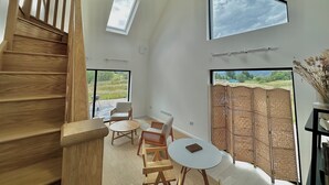 Una habitación amplia con una escalera de madera, un tragaluz, un ventanal grande y vistas a un campo.