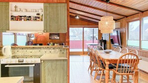 Eine gemütliche Küchenzeile im Chalet-Stil mit Essbereich, Holzböden und einem großen Fenster mit Blick ins Freie.
