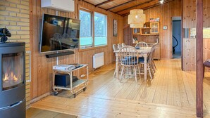 Ein gemütliches Blockhaushaus-Interieur mit Kamin, Holztisch, Stühlen und Fernseher.