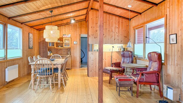 Ein gemütliches Blockhaus-Interieur mit einem Holzespeisetisch, Stühlen, einer Couch und einer kleinen Küchenzeile.