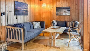 Ein gemütliches Blockhaus-Interieur mit zwei Sofas, einem Holztisch und einem Korbstuhl.