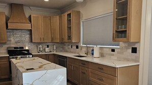 Eine moderne Küche mit Holzausstattung, einer Marmorinsel und einem eingebauten Backofen.