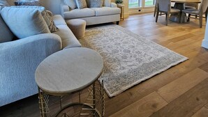 Uma sala de estar espaçosa com um sofá grande, uma mesa de centro redonda e um espaço de jantar com mesa e cadeiras.