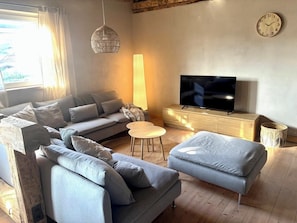 A modern living room with a sofa, a television, a lamp, and a clock on the wall. - Gude Zeit vacation home near Geierlay & Mosel (Mörsdorf)