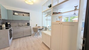 Eine moderne Küche mit hellem Holzkorpus, einem Essbereich mit rundem Tisch und Blick ins Grüne.