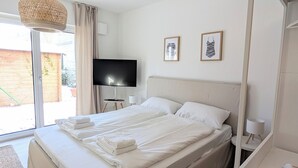 Ein Hotelzimmer mit einem großen Bett, einem Flachbildfernseher, zwei gerahmten Bildern und einem Fenster mit Vorhängen.