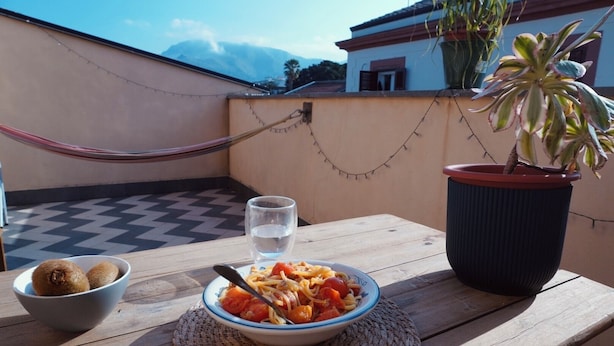 A table with a bowl of spaghetti, a glass of water, and a potted plant. - Cozy apartment with private terrace in Kalsa, in the heart of Palermo (Palermo)