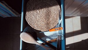 A kitchen area with a woven basket hanging on a blue metal rack, a wooden spoon, and a metal whisk on a countertop. - Cozy apartment with private terrace in Kalsa, in the heart of Palermo (Palermo)