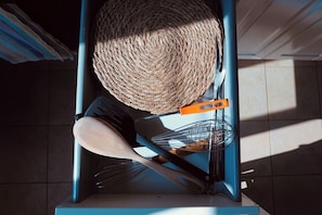 A kitchen area with a woven basket hanging on a blue metal rack, a wooden spoon, and a metal whisk on a countertop. - Cozy apartment with private terrace in Kalsa, in the heart of Palermo (Palermo)
