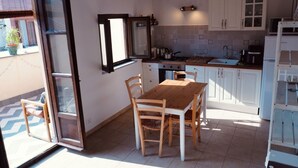 A kitchen with a wooden table and chairs, white cabinets, and a tiled backsplash. - Cozy apartment with private terrace in Kalsa, in the heart of Palermo (Palermo)