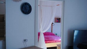 A bedroom with a bed, a bedside table, a TV, and a bookshelf. - Cozy apartment with private terrace in Kalsa, in the heart of Palermo (Palermo)