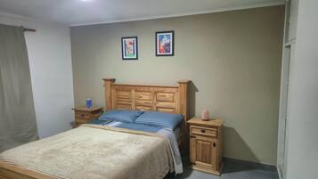 A bedroom with a wooden bed, two bedside tables, and two framed pictures on the wall.