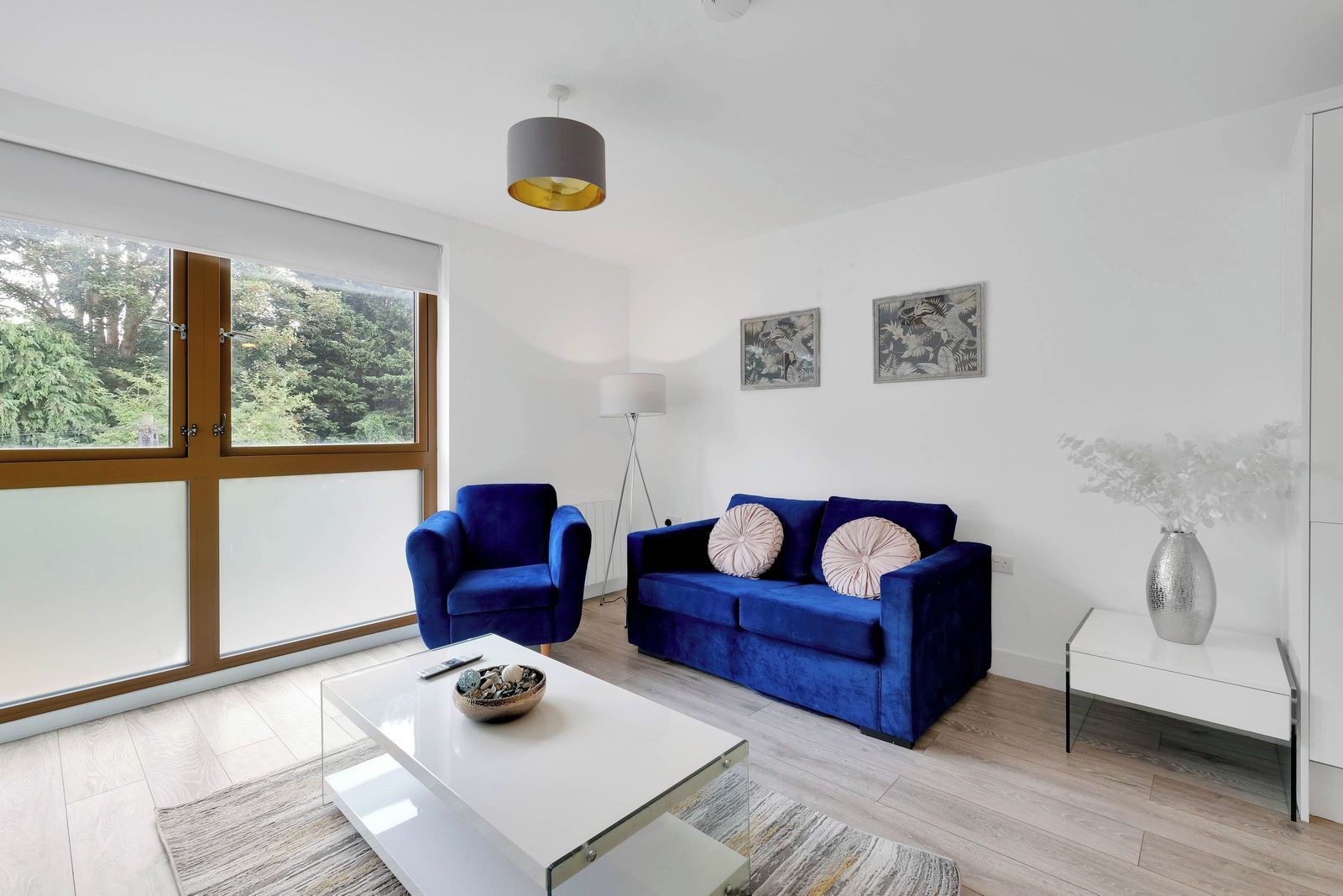 A modern living room with a blue sofa, a blue armchair, a white coffee table, and a floor lamp.