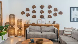 Una sala de estar con un sofá, una mesa de centro y elementos decorativos, incluyendo un cuadro en la pared y un aparador de madera.