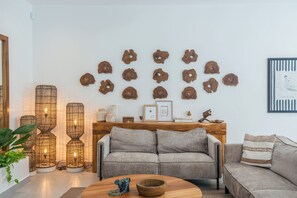 Ein Wohnzimmer mit einer Couch, einem Couchtisch und Dekorationselementen, darunter Wandbilder und eine Holzkommode.