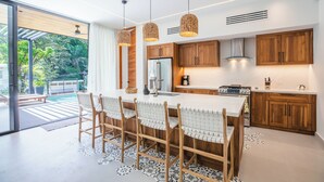 Una cocina moderna con una isla grande, armarios de madera e iluminación colgante.