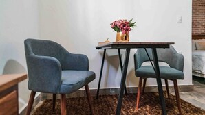 Een kleine kamer met twee stoelen, een tafel en een vaas met bloemen.