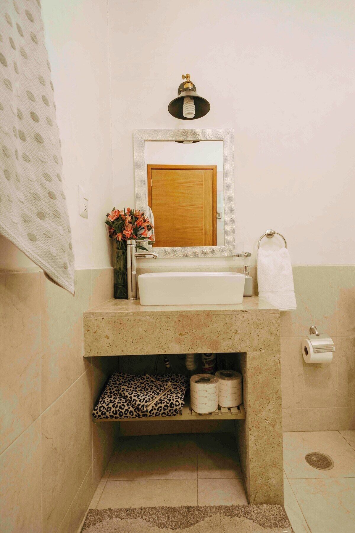 Un baño con lavamanos, papel higiénico y un perchero para toallas.