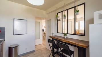 Une cuisine avec un plan de travail en bois, des chaises noires, une plante suspendue et un grand miroir.