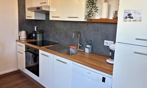 Una cocina moderna con encimera de madera, pileta de acero inoxidable, lavavajillas Bosch y muebles de cocina blancos.
