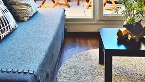 Une pièce chaleureuse avec un canapé bleu, des chaises en bois et une petite table sur laquelle est posée une plante.