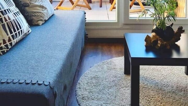 Un balcón acogedor con sofá, una mesita y un comedor.