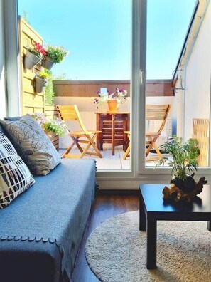 A cozy balcony with a sofa, a small table, and a dining set. - Soundproof Studio | Airport (10min) & UN (20min) (Ferney-Voltaire)