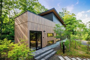 Een modern huis met een houten gevel, grote glazen deuren en een klein terras.