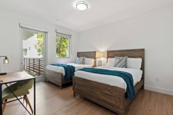 Un dormitorio con dos camas, cabecero de madera, un escritorio y una silla.