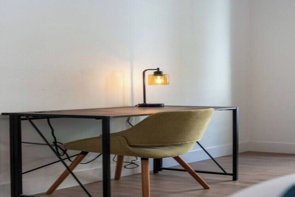 Ein modernes Zimmer mit einem Holztisch, einem gelben Stuhl und einer Stehlampe.