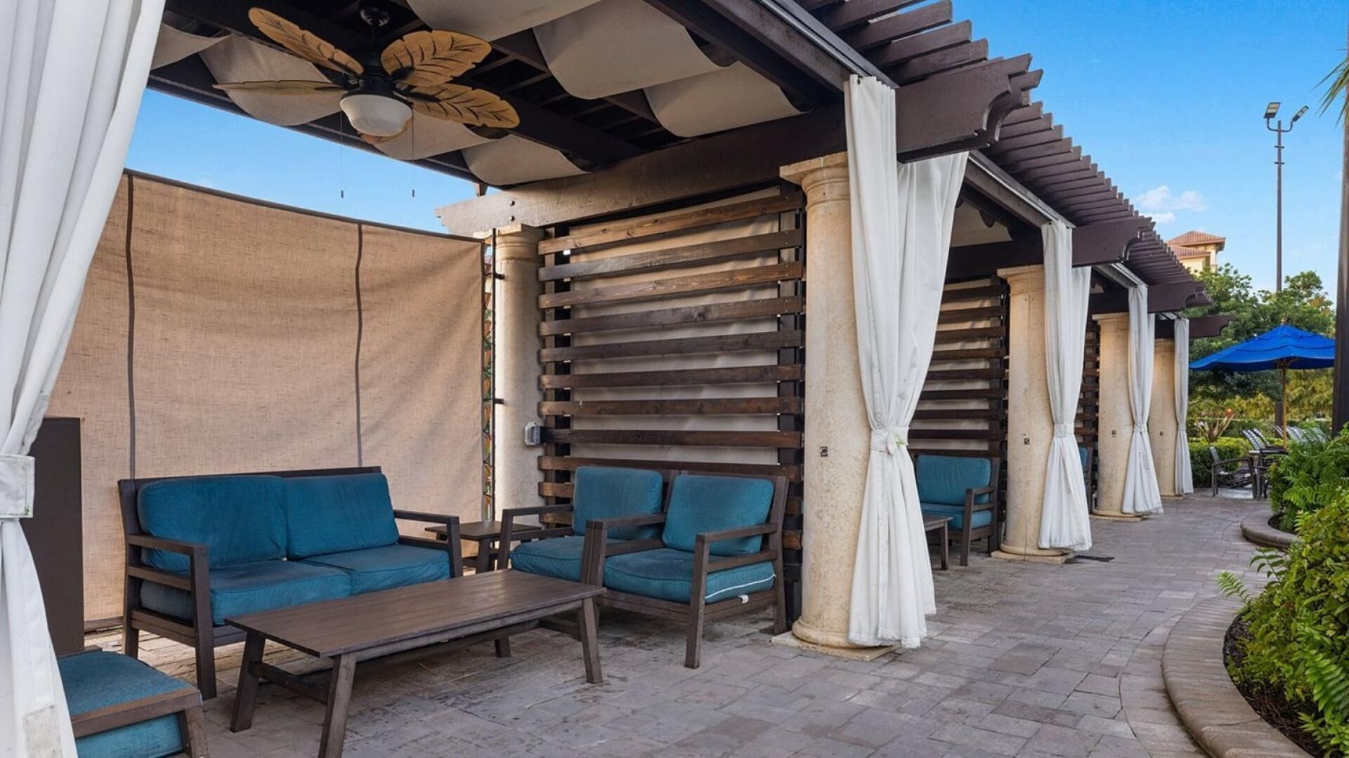 Un espacio al aire libre con mobiliario de madera y una estructura de pérgola.