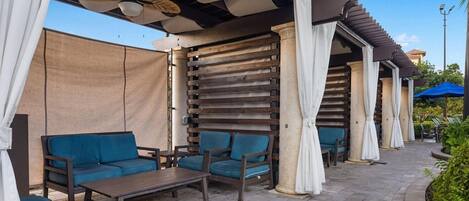 Un espacio al aire libre con mobiliario de madera y una estructura de pérgola.